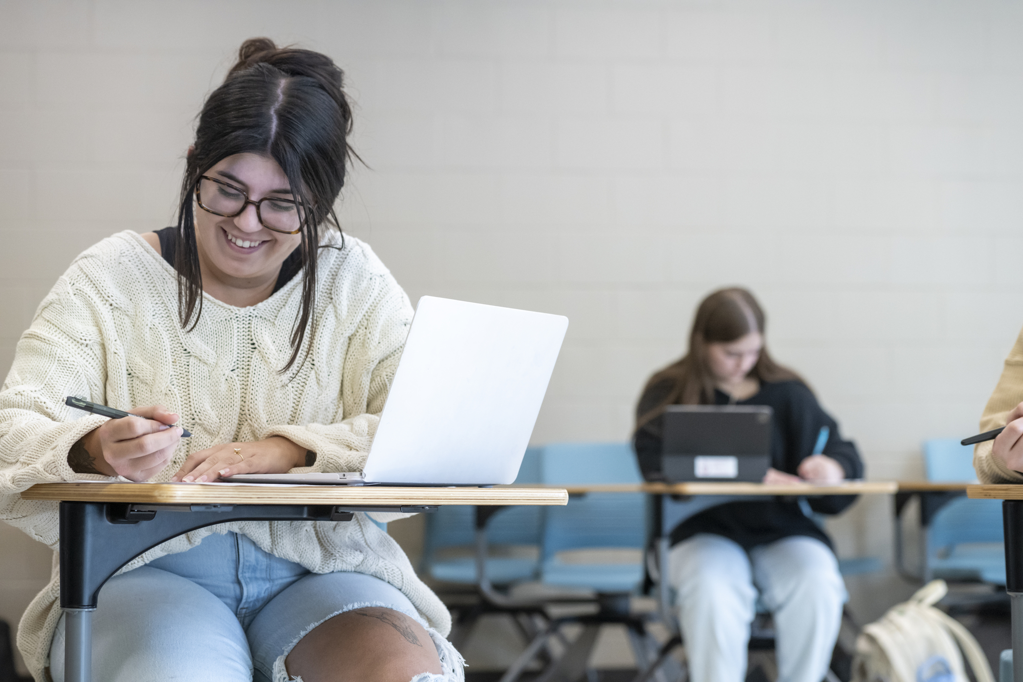 A smiling student takes notes in a classroom at Southeast.