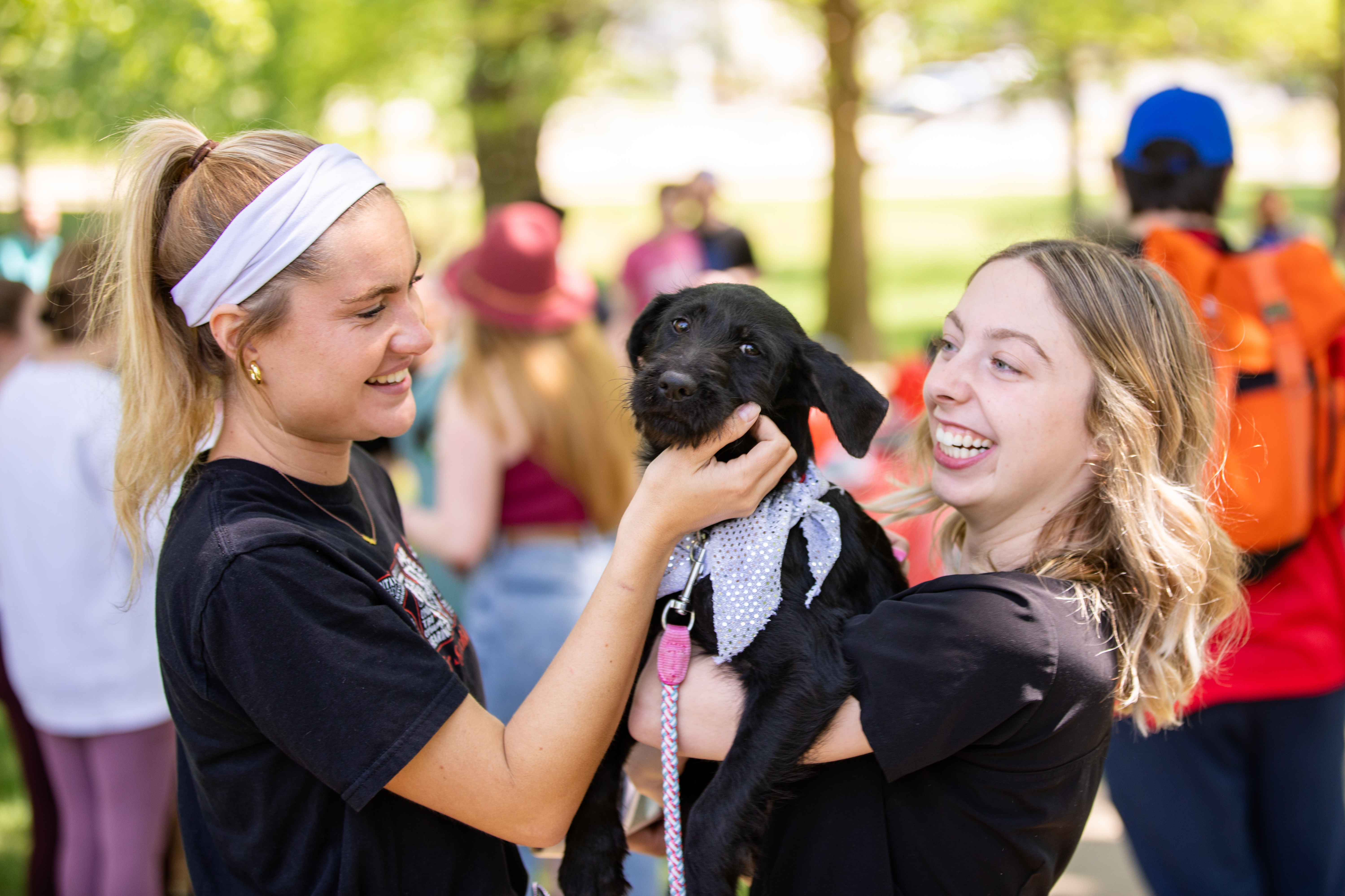 Two students smiling and holding a puppy.