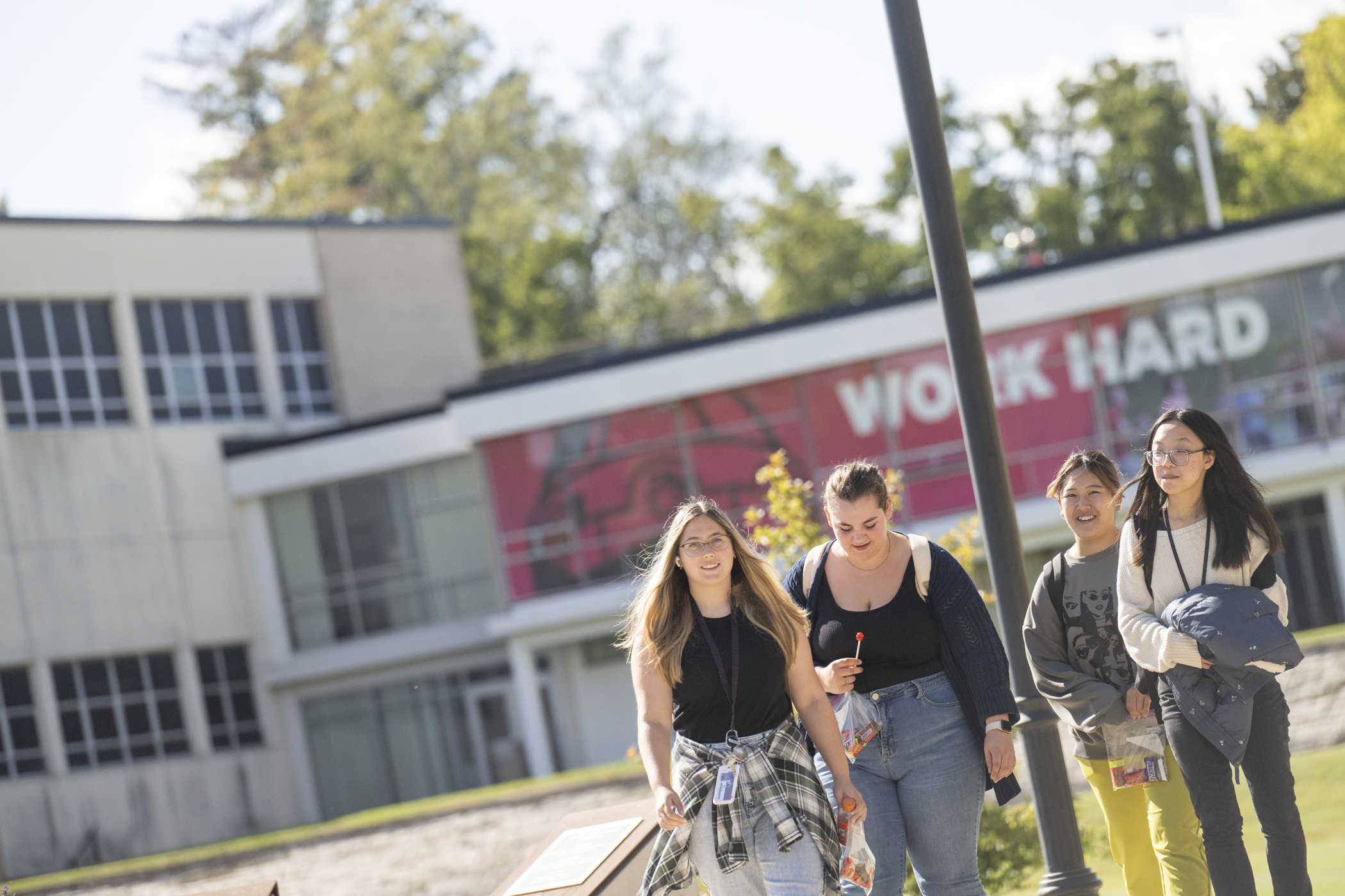Four students walk on campus on a sunny day.