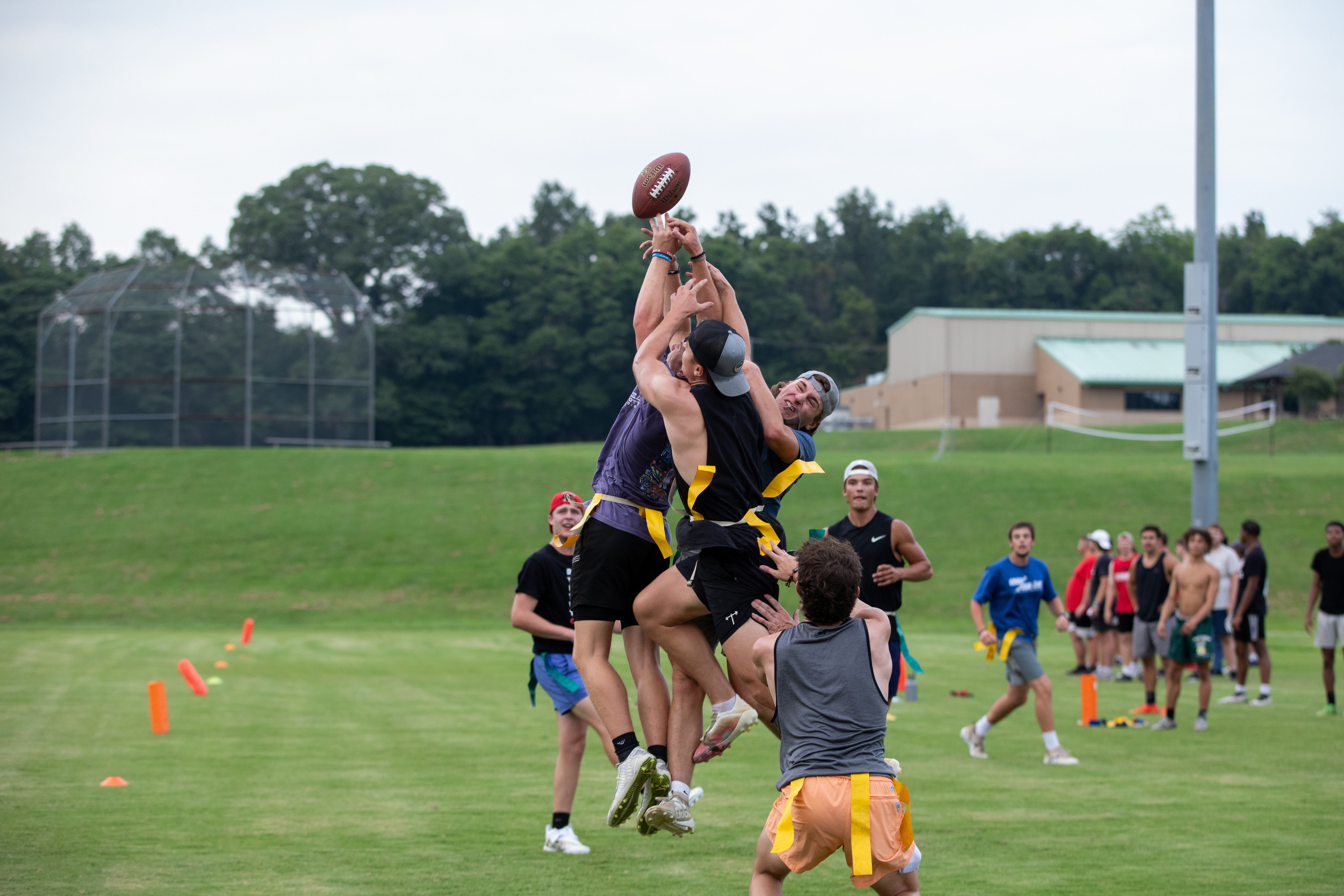college boys playing intramural flag football, all jumping up for the ball