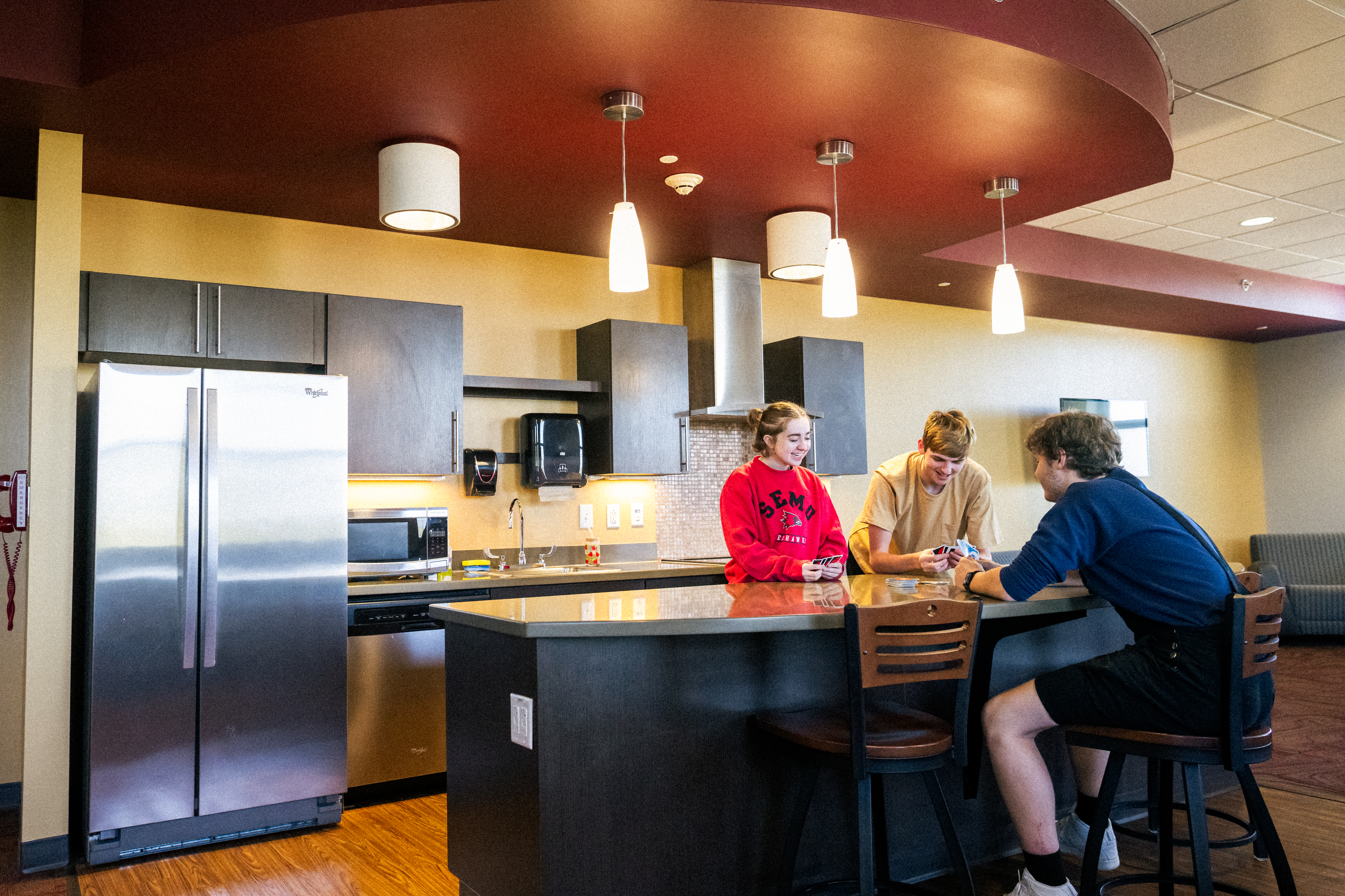 Three college students at Southeast Missouri State University playing Uno in a ResLife dorm common room lounge kitchen.