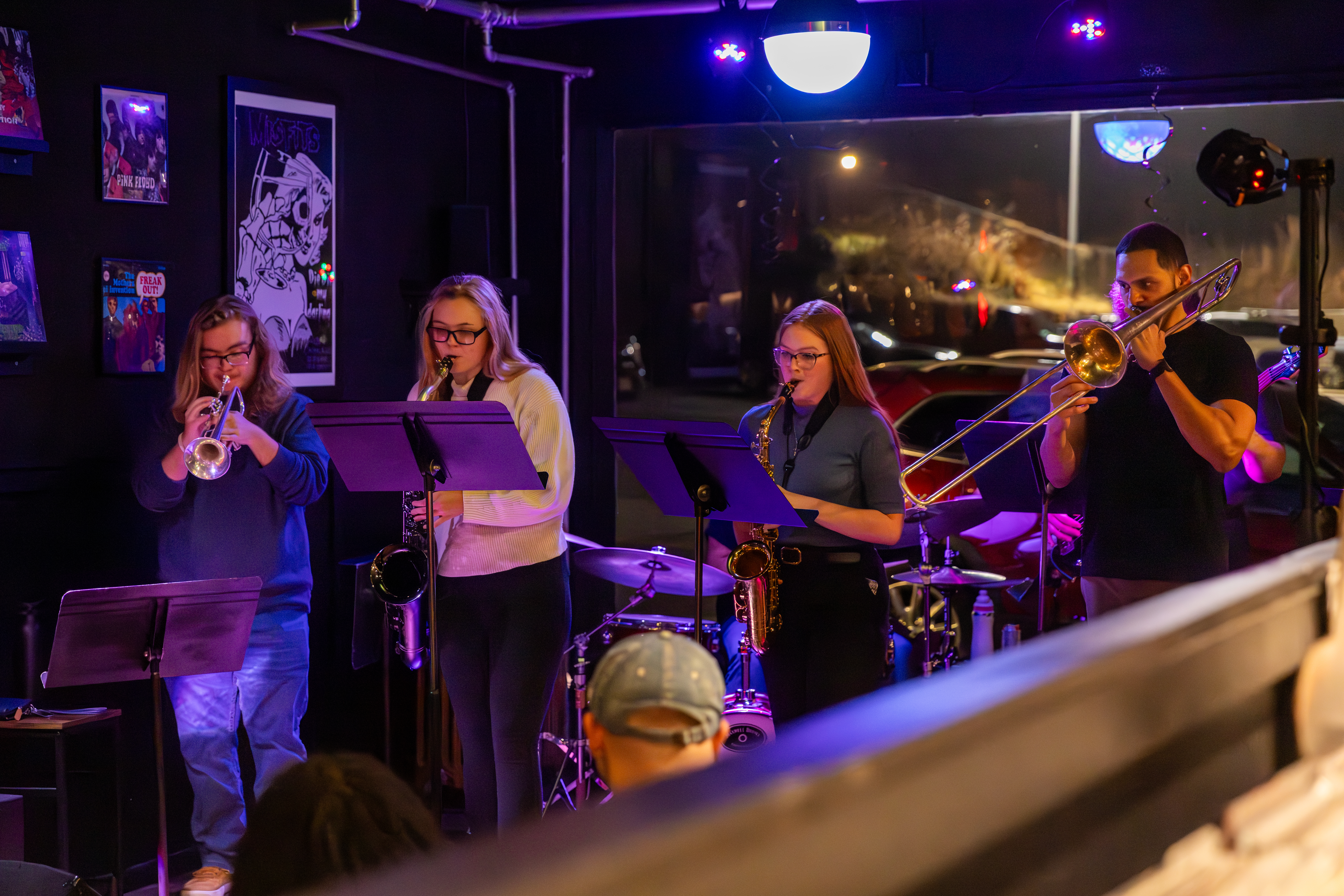 3 SEMO Music students and professor Brito playing brass instruments on stage at Spectrum Record Lounge in downtown Cape Girardeau