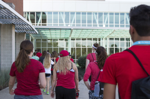 A tour group of students wearing red entering the River Campus