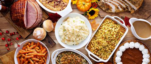 A full Thanksgiving meal laid out on a table pictured from above.