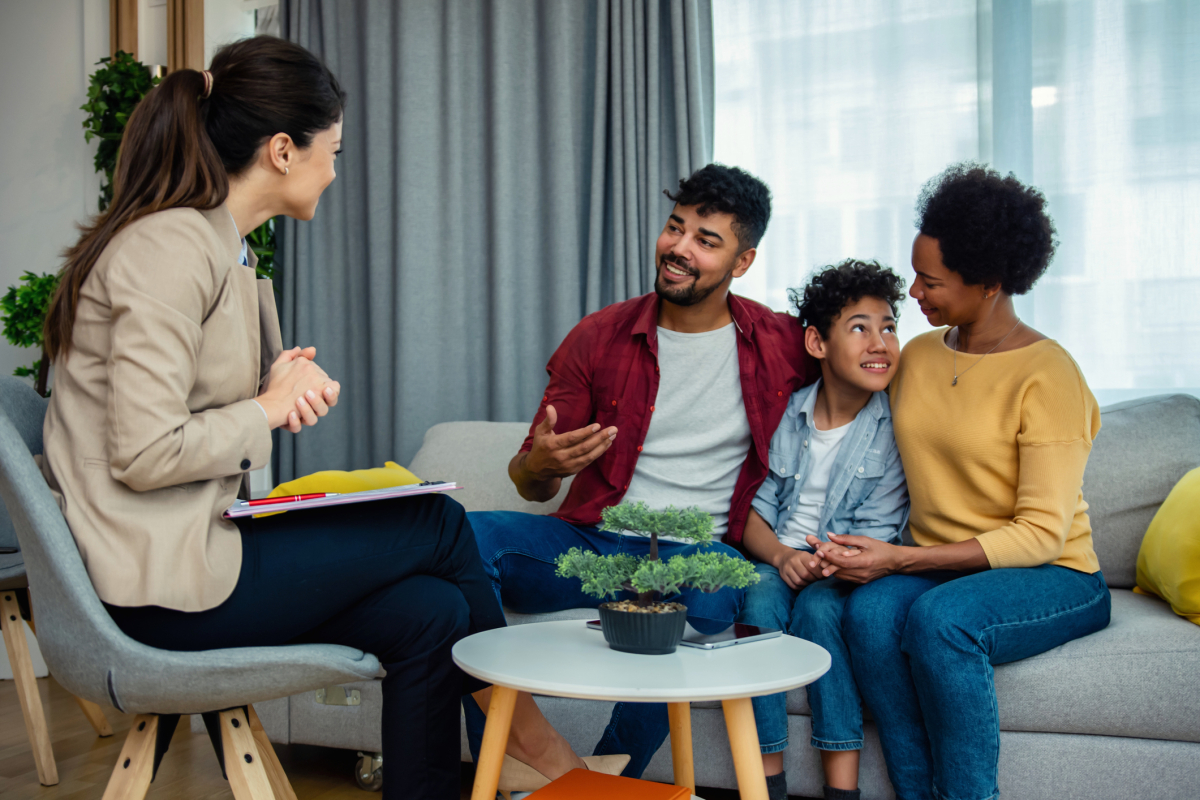 A certified family life educator talks with a family in an office. 