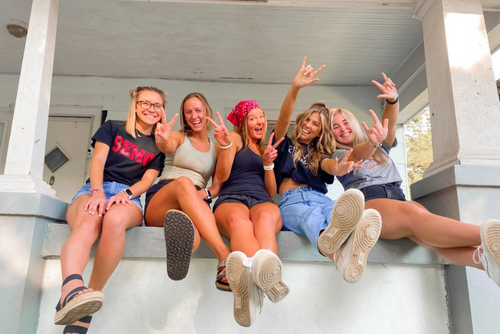 Erica and friends smile on their front porch.
