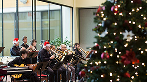 A band plays behind a brightly decorated Christmas Tree.
