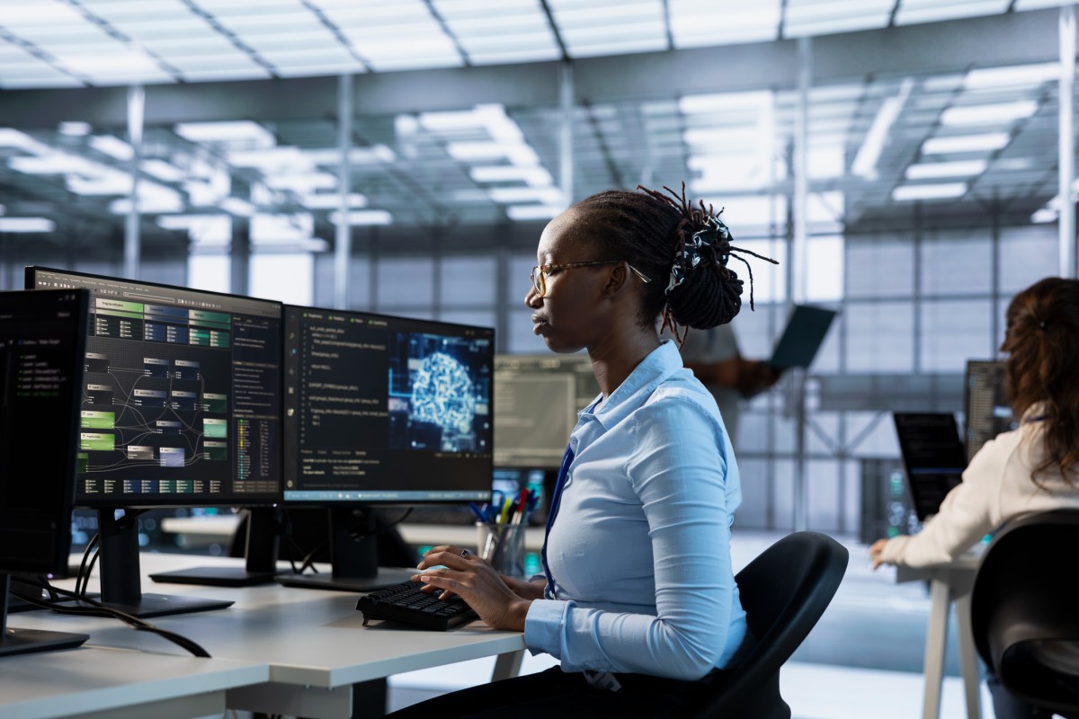 A computer scientist works at a pair of monitors in a data center.