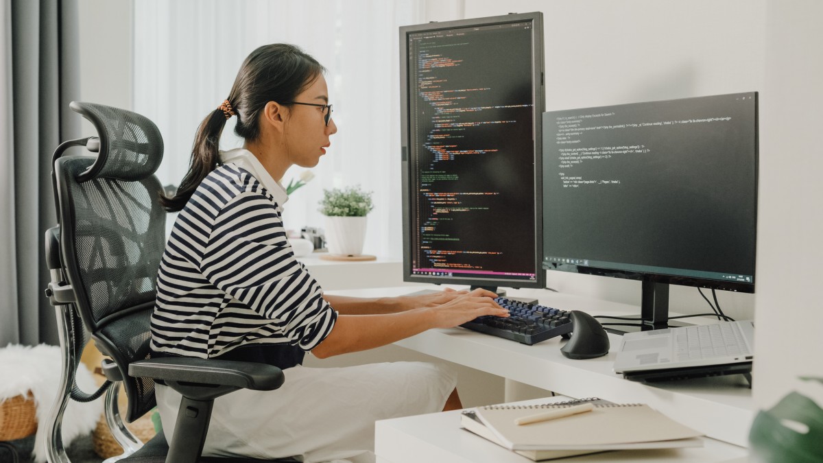 A computer scientist writes code on a desktop computer.