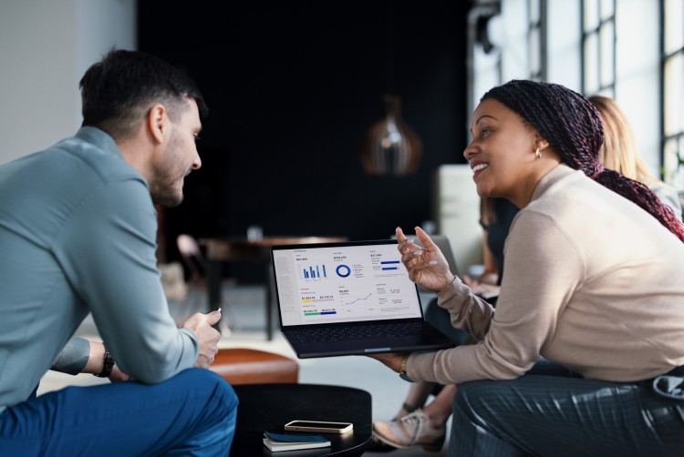 Two professionals reviewing data on a laptop in the office.