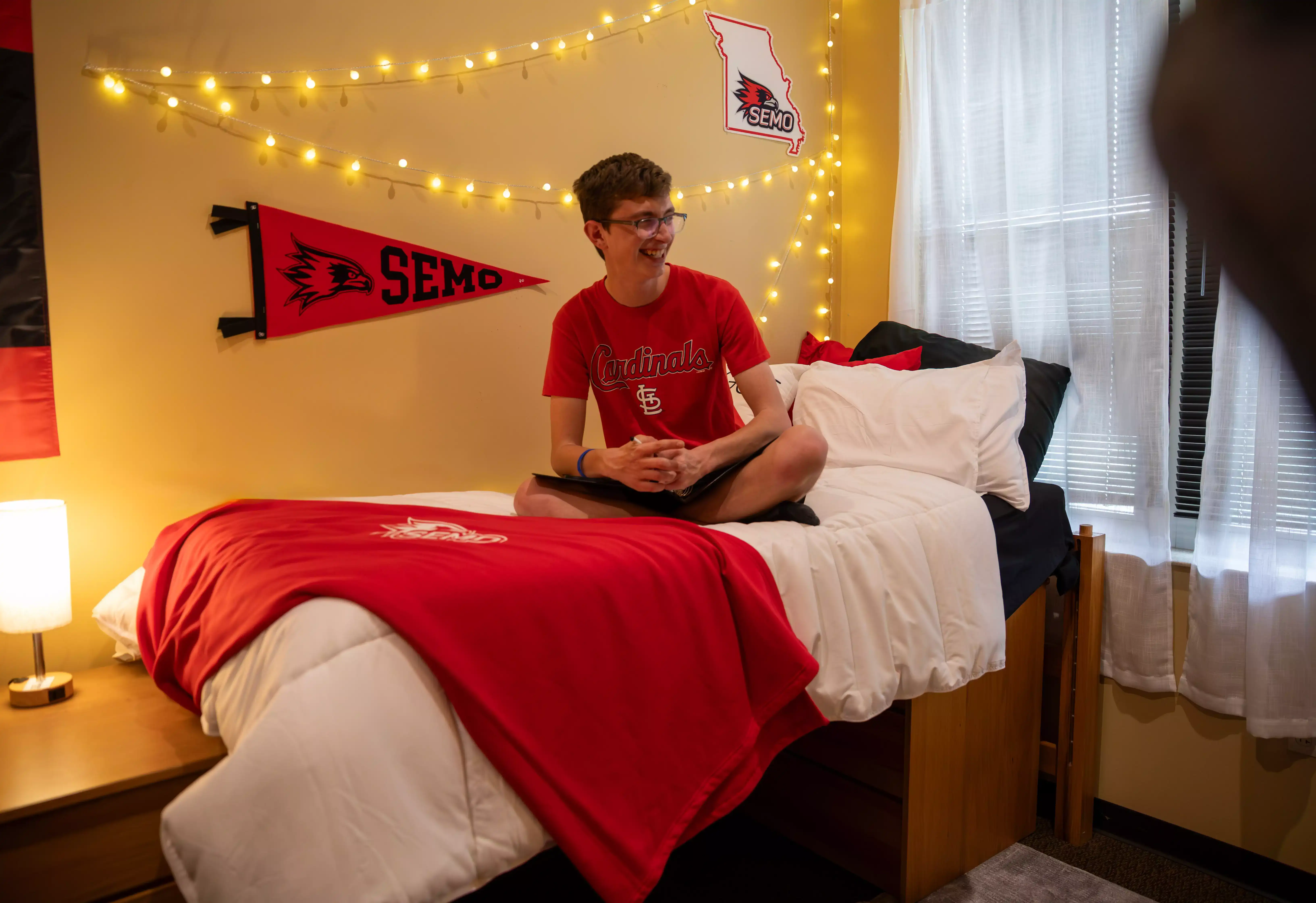 SEMo student sitting on their dorm bed with cute decorations in the background for dorm decor ideas