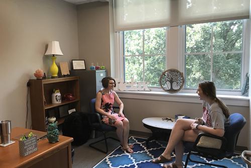 A student and a counselor sit in a room while having a session.