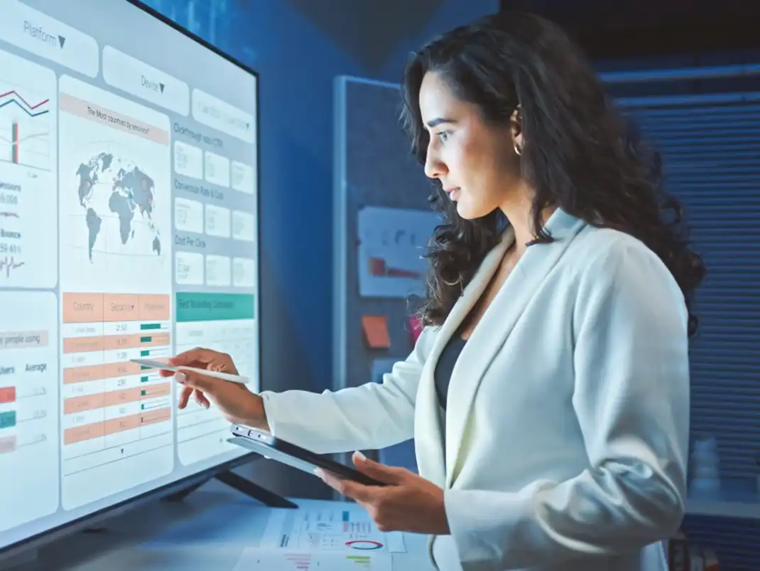 A healthcare data management professional reviews a data visualization dashboard on a smartboard.