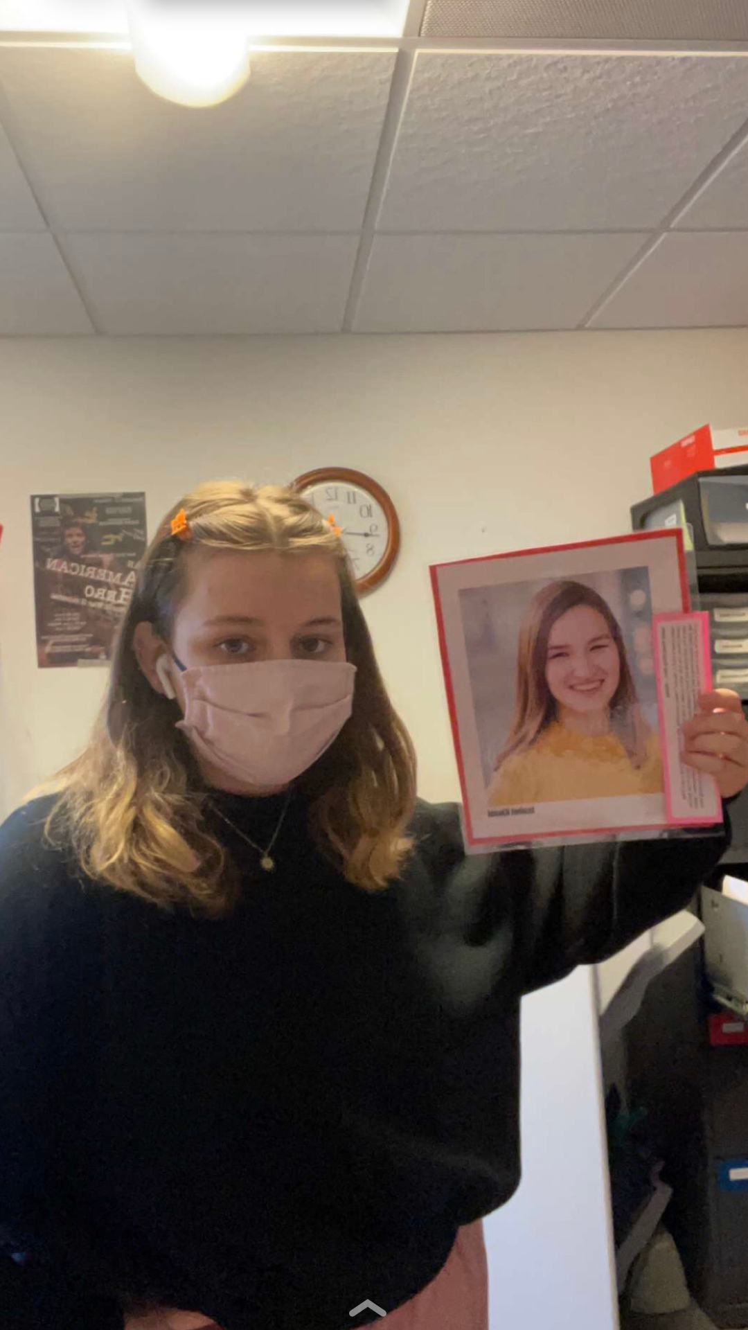 A woman holding a photo of Isabel while staring directly into the camera