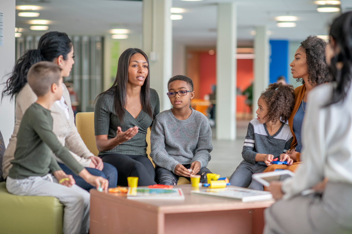 A family therapist talks with a group of parents and children.