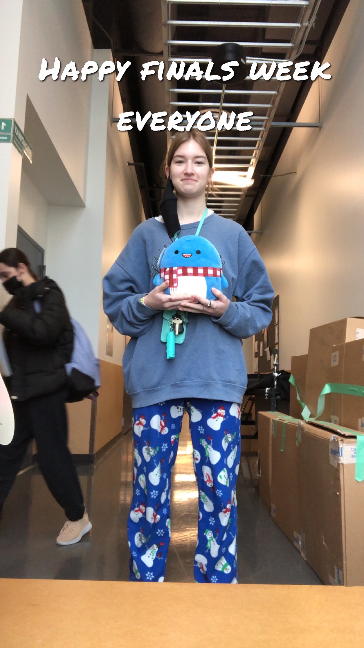 Isabel is standing in a hallway dressed in holiday pajamas holding two thumbs up.