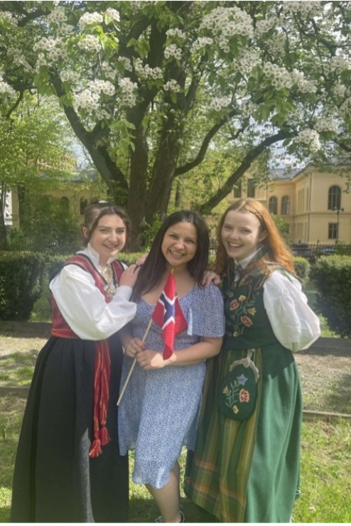 Jessica with two friends in Norway. She is wearing a dress and they are both wearing traditional Norwegian clothes for a celebration.