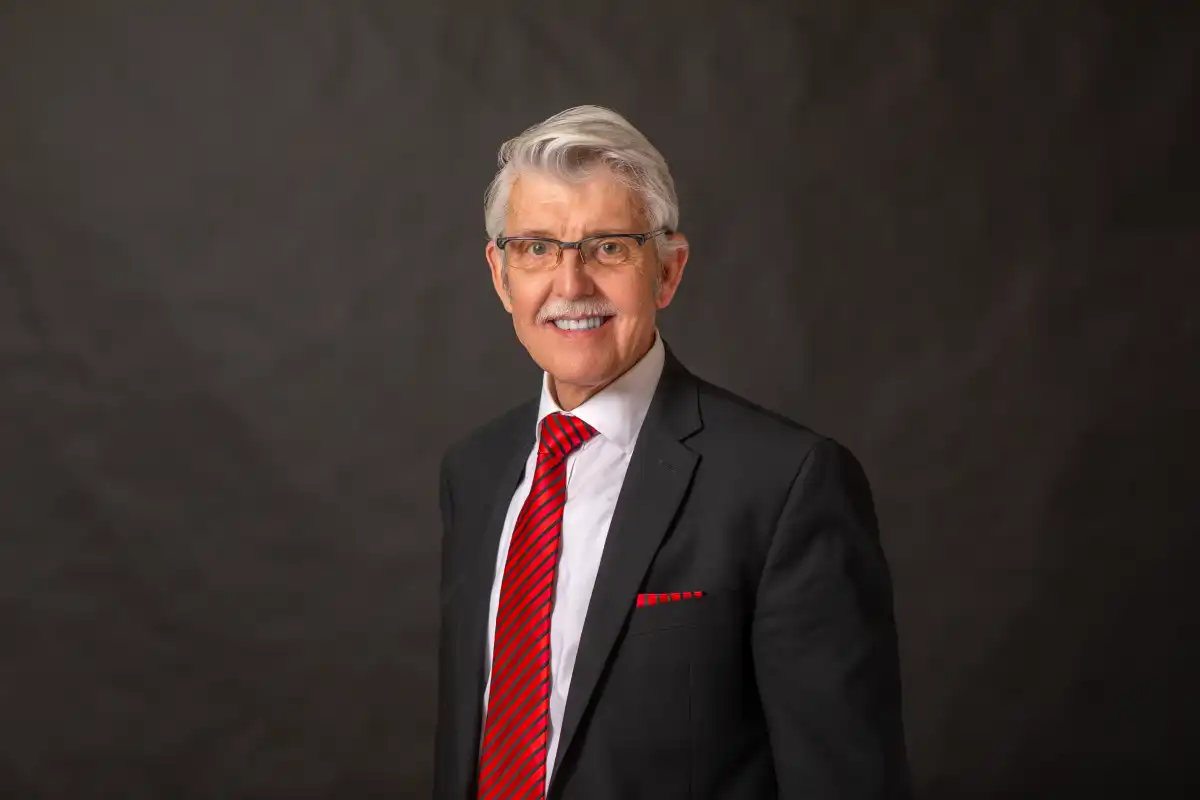 larry bohannon professional headshot dressed in a blakc suit with a red striped tie