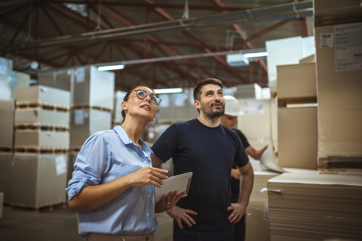 A logistics manager chats with a team member on the warehouse floor.
