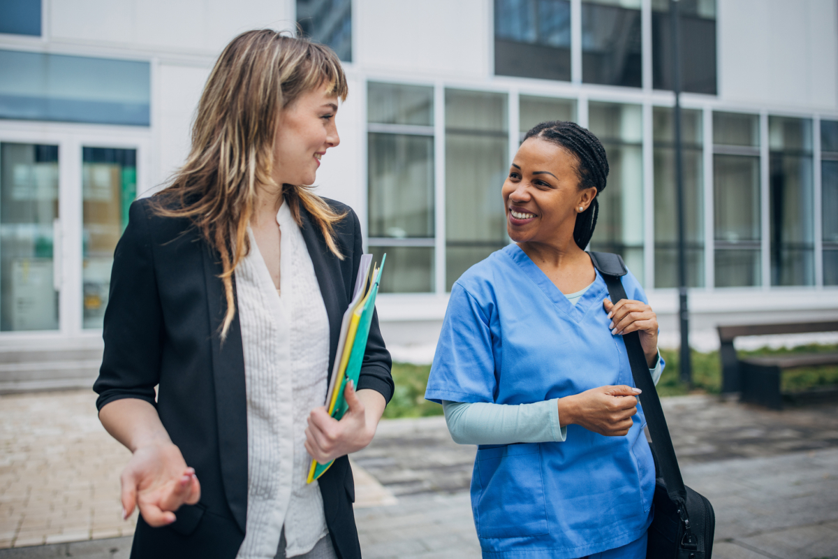 A nursing department administrator chats with a nurse as they leave the hospital. 