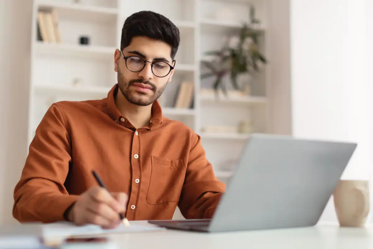 An MBA student takes notes while participating in an online class. 