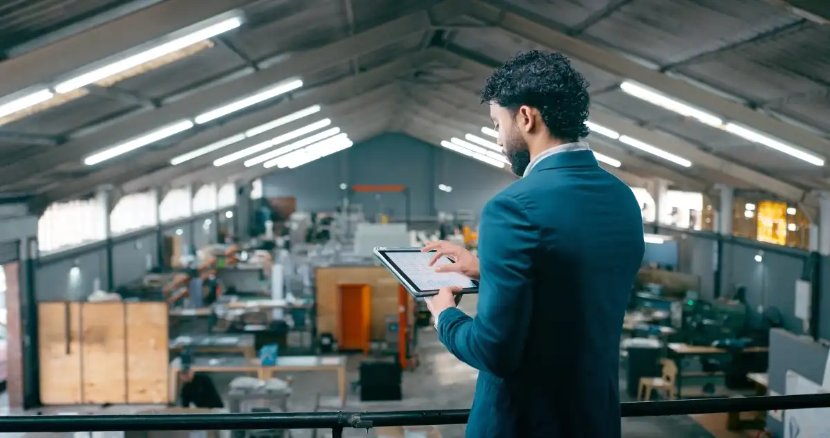 An operations manager works on a tablet and looks down at the warehouse floor.