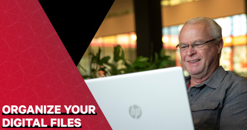 A older man smiling at his laptop screen with a red, angled, graphic overlay.