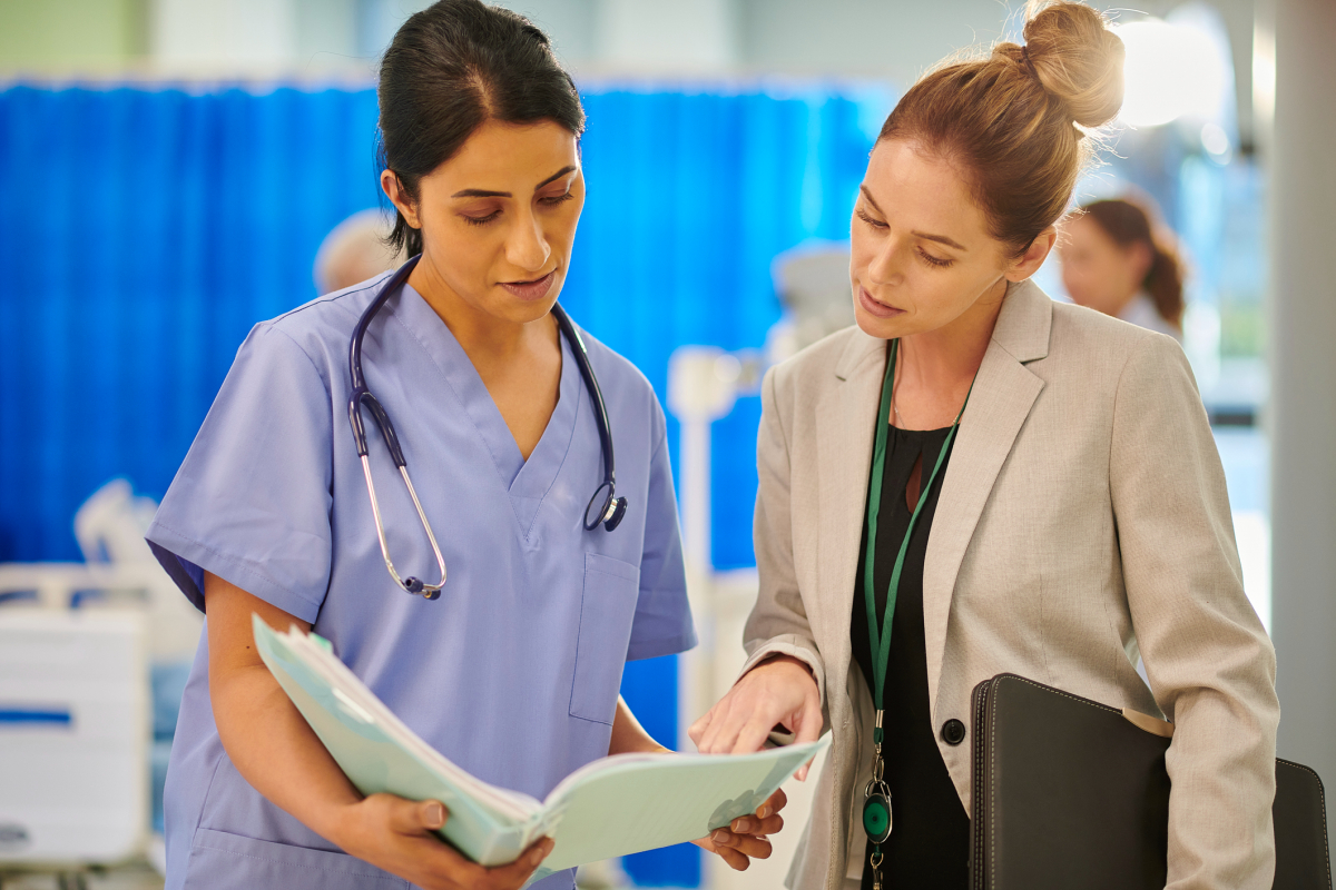 A patient safety specialist talks to a nurse in a hospital.