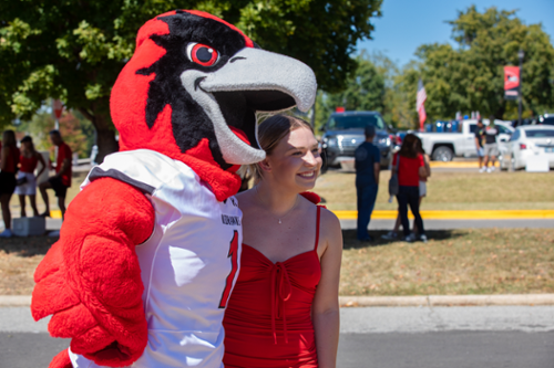 Fan taking a photo with SEMO's mascot Rowdy the Redhawk. 