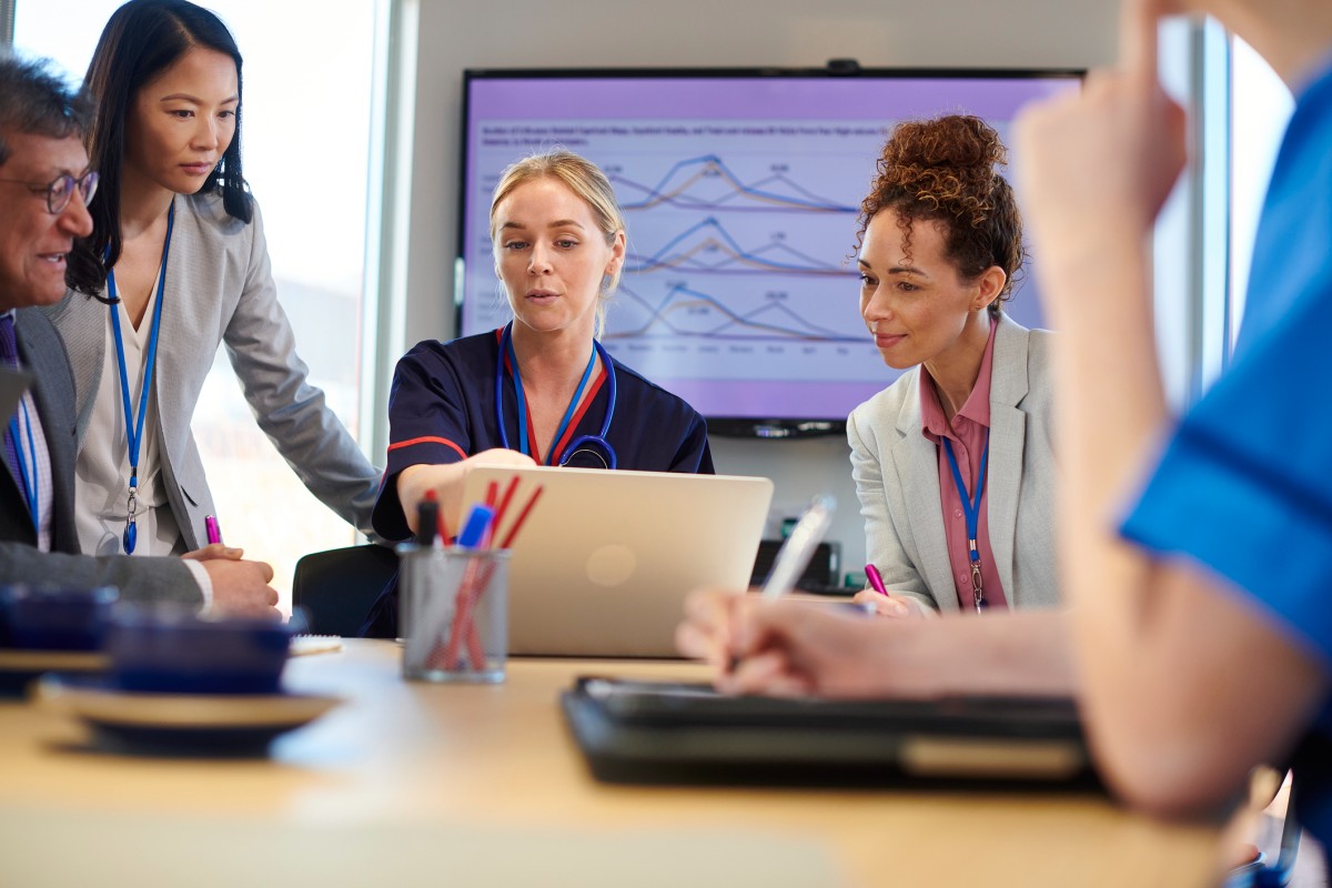 A team of quality improvement specialists reviews data on a laptop with clinicians.