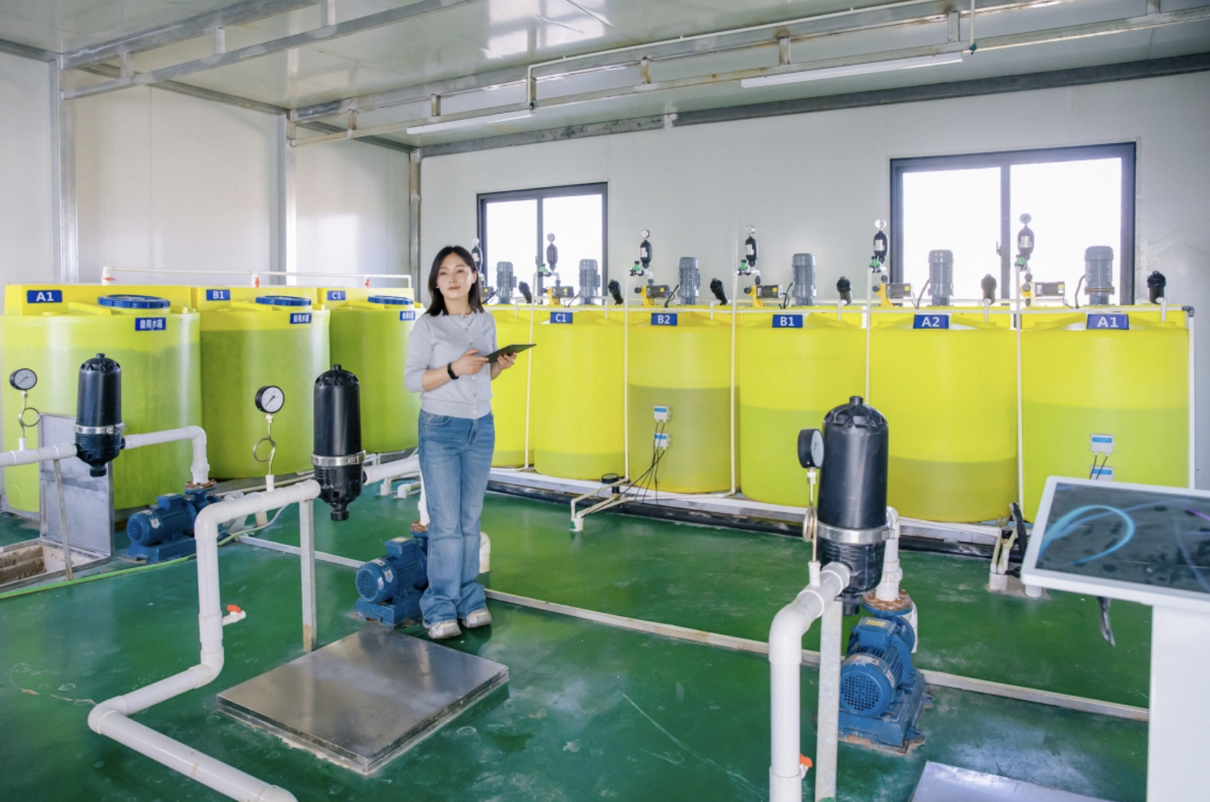 A farm manager checks on the water and fertilizer system in a greenhouse.