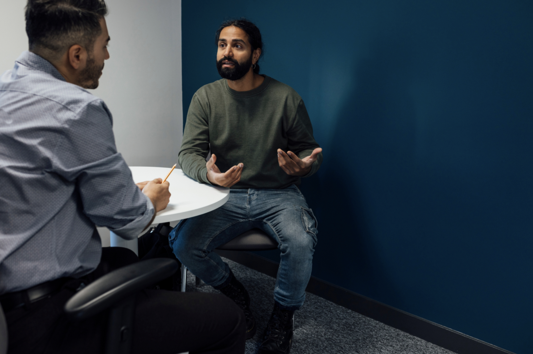 A probation officer speaks with a probationer in an office.