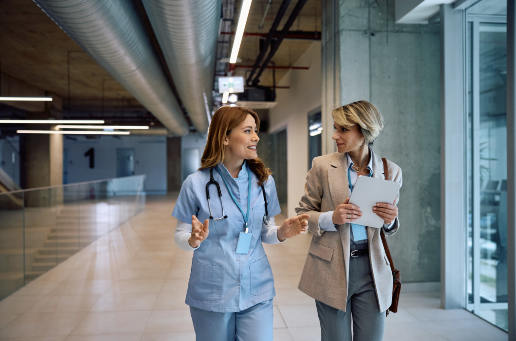 A healthcare administrator talks with a nurse in a hospital.