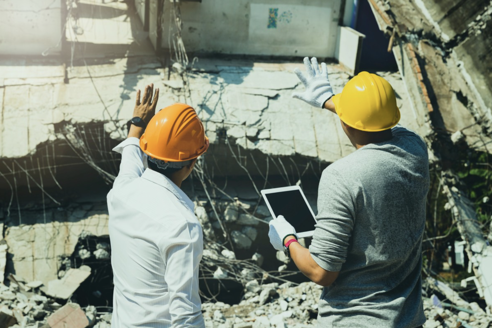 An emergency management director surveys building damage with a construction worker.