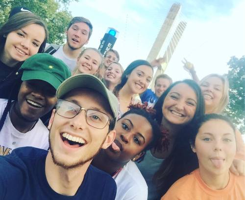 A selfie of a group of students from the Towers North 8th Floor in front of the bridge of River Campus