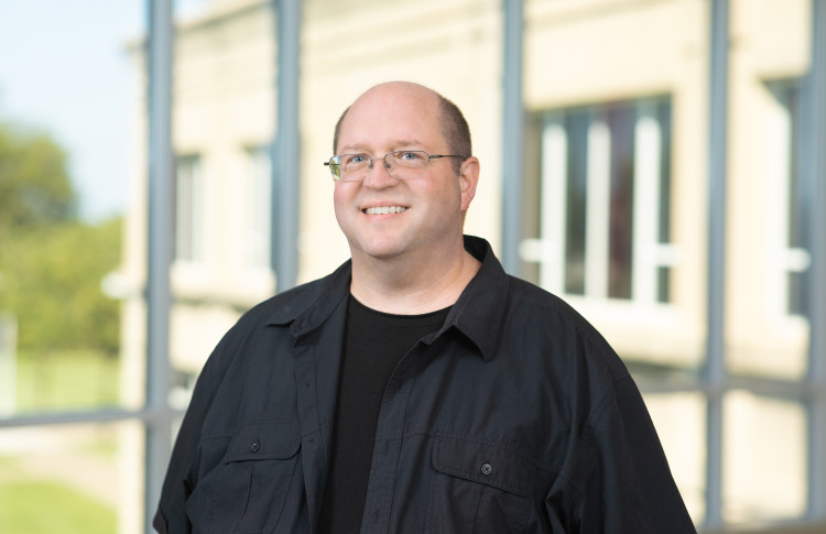Professor Shawn Guiling standing in a hallway in front of a window.