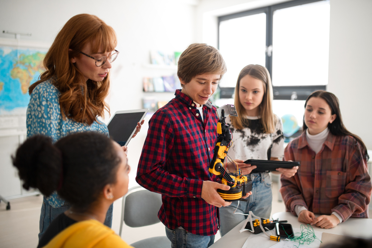 A teacher watches as a student demonstrates a robotic toy in the classroom.