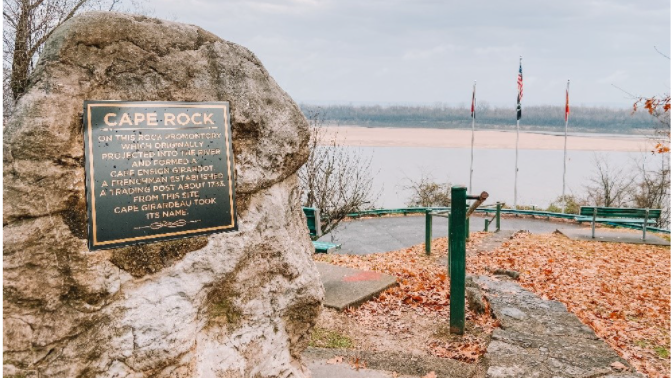 A rock overlooking the river with a plaque that read "Cape Rock" there is additional text on the plaque explaining the history behind the rock.