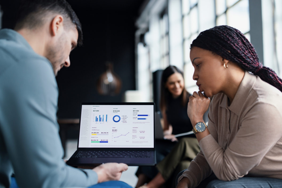 Business data analysts review some visualized reports on a laptop.