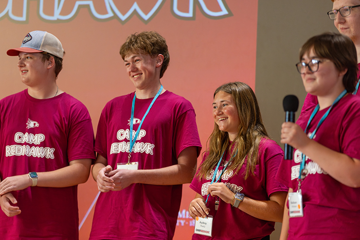 Camp Redhawk attenders stand on a stage.