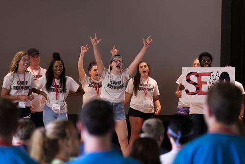 A group of students on stage engage with the audience to promote SEMO spirit at Camp Redhawk.