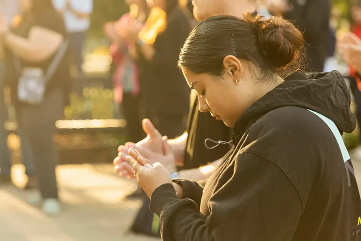 a SEMO student participating in the Patriots' Day ceremony folds her hands and prays