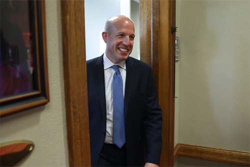 Image of Chad Lich smiling as he walks through a doorway.