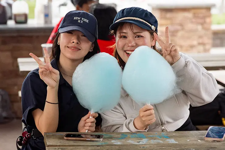 Two SEMO students holding cotton candy flash peace signs for the camera