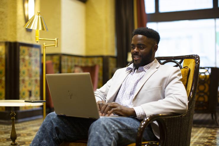A student sits in a chair to work on their laptop at the Marquette Hotel. 