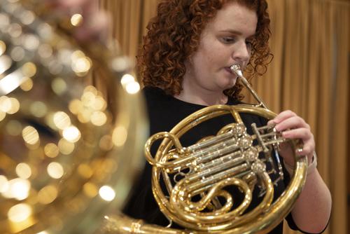 A horn studio student plays the French horn during a performance.