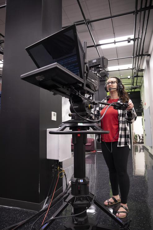 A TV/film student watches the back of a camera while filming in the studio at Rust Center for Media.