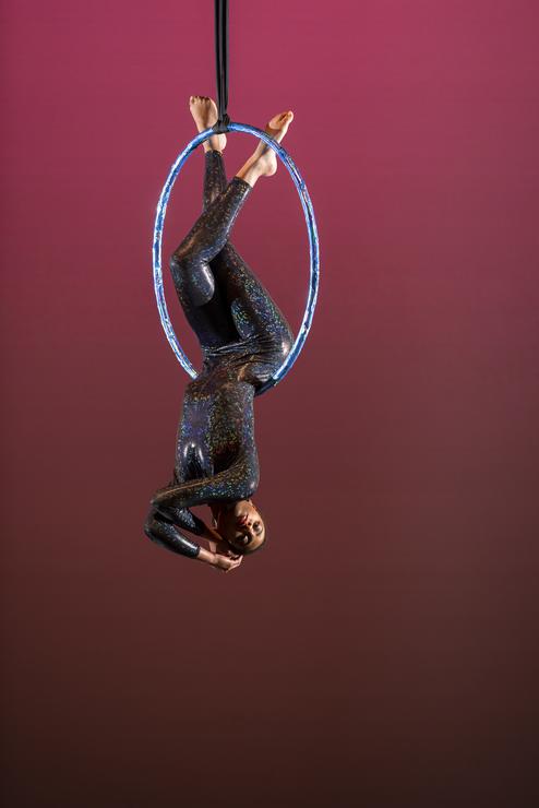 A dance student performs with a large hoop during an aerial routine.