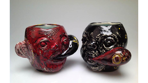 Two ceramic mugs. One is red and one is black. They both have faces carved into them. 