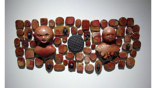 A display of ceramic pieces of various sized and shapes. Two pieces depict busts of heads. 